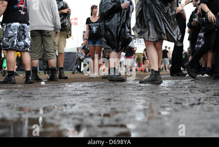 Besucher des Festivals stehen vor einer Pfütze Schlamm beim Wacken Open Air Festival in Wacken, Deutschland, 2. August 2012. Die weltweit größte Heavy Metal Festival findet vom 02 bis 4. August 2012. Foto: DANIEL REINHARDT Stockfoto