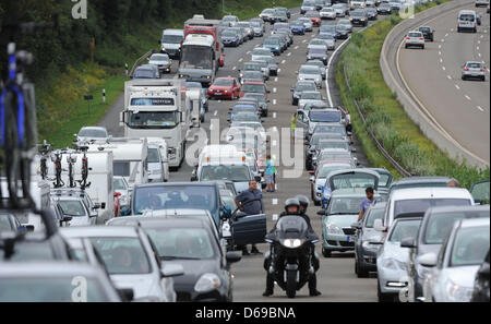 Menschen stehen neben ihre Autos auf der Autobahn A7 bei einem Stau in der Nähe von Bad Hersfeld, Deutschland, 5. August 2012. Das Ende der Schule Hlidays verursacht mehrere Verkehr Marmeladen in ganz Deutschland am Wochenende. Foto: JULIAN STRATENSCHULTE Stockfoto