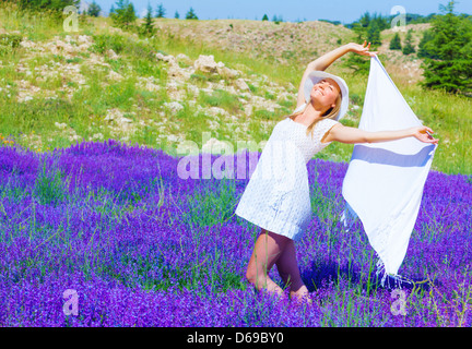 Schöne blonde Frau hält in Händen weißen Schal und tanzen in Lila Lavendel Blumenfeld, sonnigen Tag, Sommersaison Stockfoto