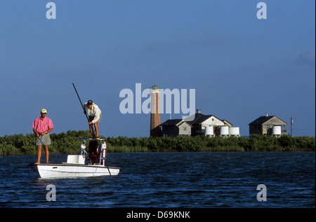 Zwei Männer poling ihr Boot und Angeln für Bachsaibling und Rotbarsch in der Nähe von Lydia Ann Lighthouse an Port Aransas Texas Stockfoto