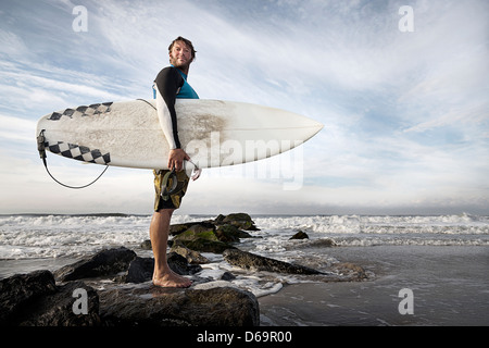 Surfer, die auf Felsen am Strand Stockfoto