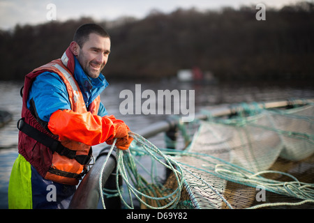 Worker bei Lachsfarm im ländlichen See Stockfoto