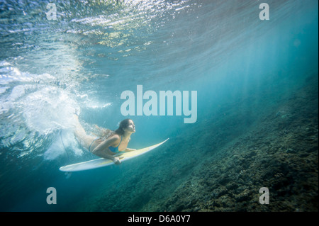 Surfer unter Welle in Wasser tauchen Stockfoto
