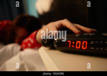 Wecker früh mit Anfang zwanzig Frau liegen im Bett in einem Schlafzimmer Alarm ausschalten Stockfoto