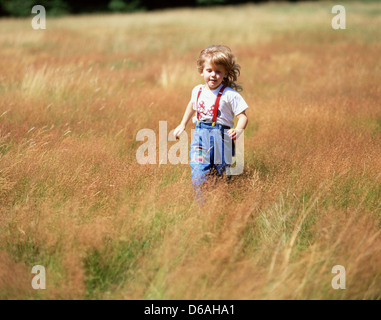 Junges Mädchen läuft durch Wiese, Winkfield, Berkshire, England, Vereinigtes Königreich Stockfoto