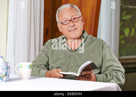 Ältere Mann ein Buch mit Lesebrille in einem Altenheim Stockfoto