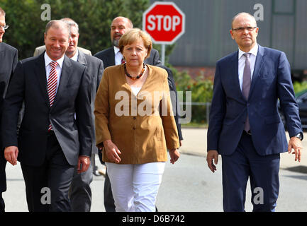 Bundeskanzlerin Angela Merkel, Premier of Mecklenburg-Western Pomerania Erwin Sellering (R) und Manager von P + S-Petkumer in Stralsund und Wolgast Rüdiger Fuchs (L) geben ein Statement am Eingang der Volksweft-Werft in Stralsund, Deutschland, 21. August 2012. Merkel nahm Teil in einer Besprechung über die Zukunft der Schiffbau-Unternehmen, wo waren Vertreter der Medien nicht gestattet. Stockfoto