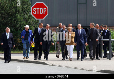 German chancellor Angela Merkel (C), Premier von Mecklenburg-Western Pomerania Erwin Sellering (R von Merkel) und Manager von P + S-Petkumer in Stralsund und Wolgast Ruediger Fuchs (4-L) geben ein Statement am Eingang der Volksweft-Werft in Stralsund, Deutschland, 21. August 2012. Merkel nahm Teil in einer Besprechung über die Zukunft der Schiffbau-Unternehmen, wo waren Medienvertreter Stockfoto