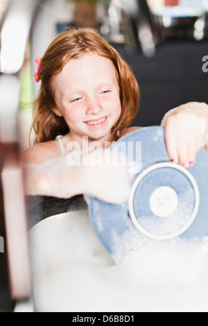 Lächelndes Mädchen Platte im Waschbecken waschen Stockfoto