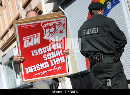 Ein Mann trägt Plakate von der extremistischen Partei NPD aus ein Haus, das von der Polizei in Dortmund, Deutschland, 23. August 2012 gesucht wurde. Die Premiere des North Rhine-Westphalia geächtet heute drei rechten extremistische Organisationen. Polizei wurden in Kraft gegen die Neonazis und Zimmer im Ruhrgebiet und in Aachen gesucht. Die Organisationen "Kameradschaft Aachener Land", Stockfoto