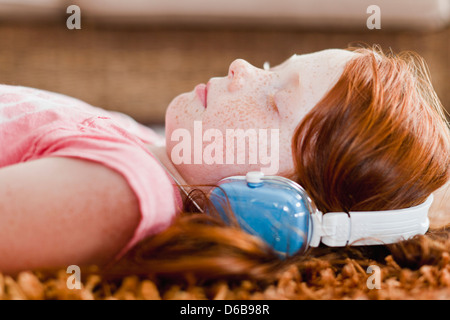 Mädchen hören Kopfhörer auf Teppich Stockfoto