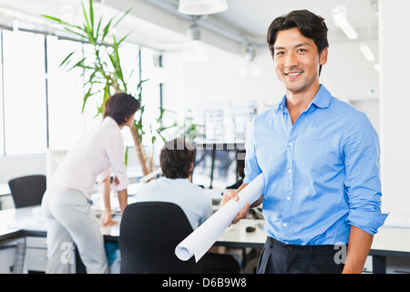 Geschäftsmann mit Blaupausen im Büro Stockfoto