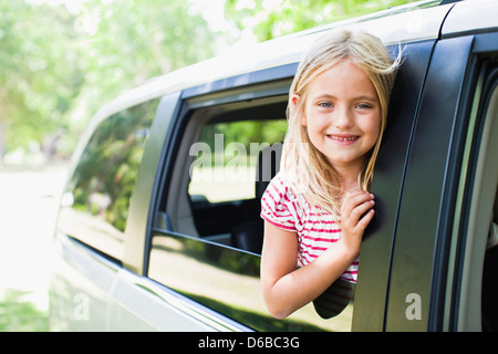 Lächelndes Mädchen stehend im Autofenster Stockfoto