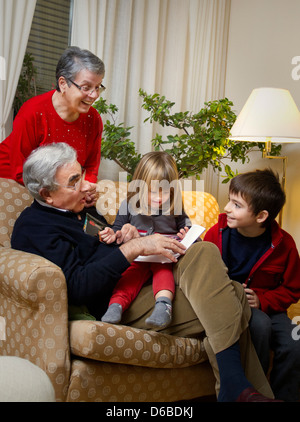 Älteres Ehepaar mit Enkelkindern auf sofa Stockfoto