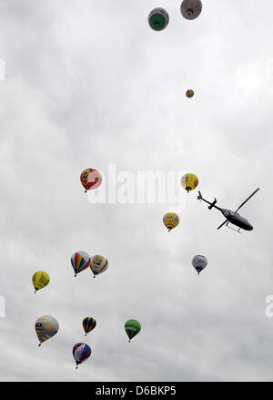 Ein Hubschrauber geht durch eine Gruppe von Heißluftballons in der Luft bei der Heißluft-Ballon-Festival "Montgolfiade 2012" in Warstein, Deutschland, 1. September 2012. Mehr als 343 Piloten mit 206 Ballons aus 11 Ländern nehmen Teil an der diesjährigen 22. Montgolfiade, die gilt als Europas größte Heißluft-Ballon-Festival. Foto: Henning Kaiser Stockfoto