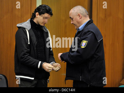 Der Beschuldigte Flughafen-Attentäter, die, den Arid Uka durch ein Wachtmeister an das Oberlandesgericht in Frankfurt Am Main, Deutschland, 9. Januar 2012 Cuff ist. Der Kosovo wird beschuldigt, zwei US-Soldaten getötet und verletzt ein anderes Grundstück zwei in ein Attentat am Flughafen in Frankfurt am 2. März 2011. Heute werden die Plädoyers von Anklage und Verteidigung erwartet. Foto: BORIS ROESSLER Stockfoto