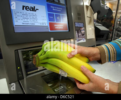 (DATEI) Eine Archivfoto vom 22. Oktober 2010 zeigt ein Kunde an eine SB-Kasse bei Real Supermarkt in Berlin-Neukölln, Deutschland. Verpackung Brot selbst oder SB-Kassen, Unternehmen Sie immer mehr Aufgaben an Kunden weiterzugeben und Kosten zu sparen. Viele finden es praktisch, aber nicht jeder. Foto: Stephanie Pilick Stockfoto