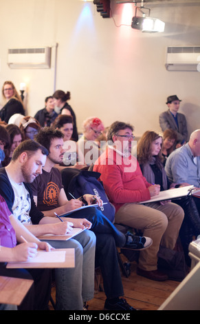 Sitzendem Publikum genießt eine Leistung und skizzieren an einen Dr. Sketchy Burlesque Aktzeichnen event Stockfoto