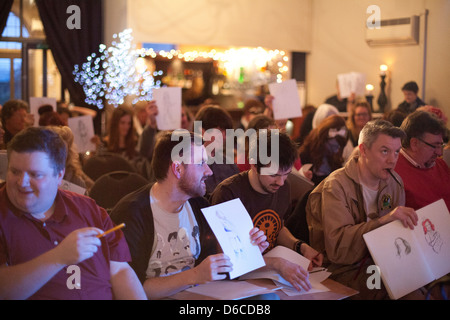 Sitzendem Publikum genießt eine Leistung und skizzieren an einen Dr. Sketchy Burlesque Aktzeichnen event Stockfoto