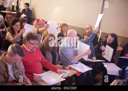 Sitzendem Publikum genießt eine Leistung und skizzieren an einen Dr. Sketchy Burlesque Aktzeichnen event Stockfoto