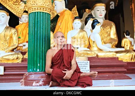 Ein Mönch sitzt vor Buddha-Statuen an der Shwedagon-Pagode in Yangon, Myanmar, 5. Februar 2013. Stockfoto