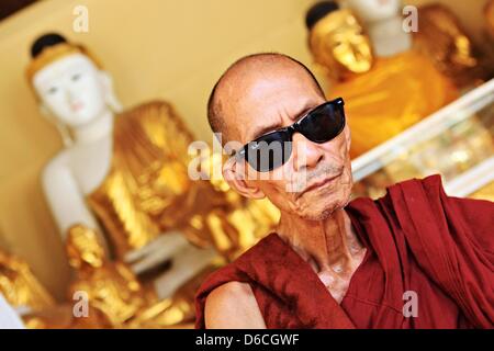 Ein Mönch mit Sonnenbrille sitzt an der Shwedagon-Pagode in Yangon, Myanmar, 6. Februar 2013. Stockfoto