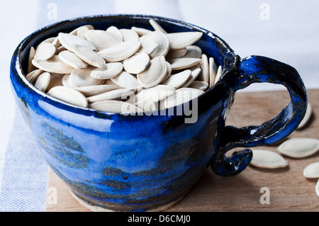 Kürbiskerne im Cup auf Holzbrett Stockfoto