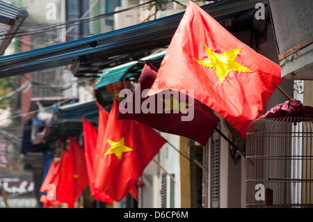 Horizontale Ansicht von vielen vietnamesischen Flaggen wehen im Wind außerhalb der Häuser. Stockfoto