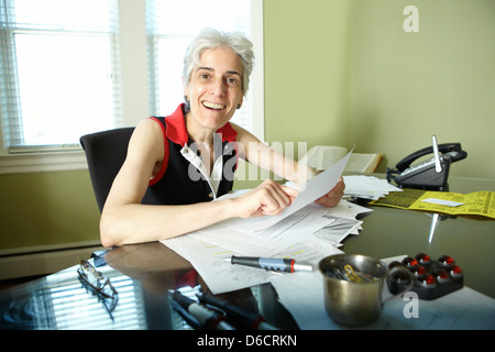 Ältere Frau liest Papiere im Büro Stockfoto
