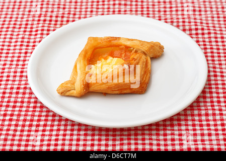 Plundergebäck mit Pfirsichmarmelade und Vanille auf einem weißen Teller serviert. Stockfoto