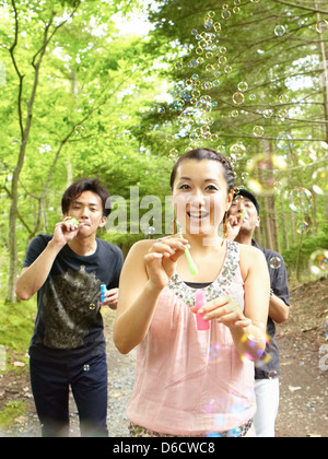 Mädchen und zwei Jungs bläst Seifenblasen auf einer Landstraße Stockfoto