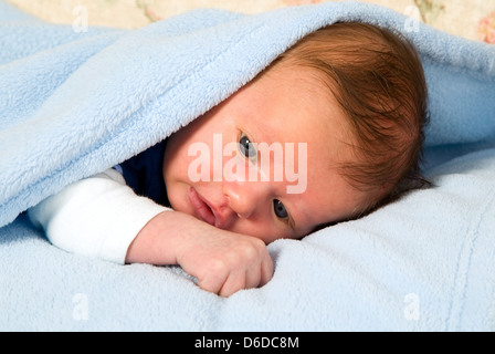 Schönen weißen Jungen mit großen Augen liegt unter Decke Stockfoto