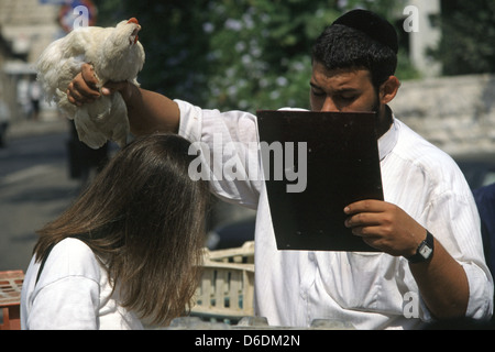 Ultra-orthodoxe Juden schwingen ein Huhn über den Kopf der Frau als Teil der Kapparot Ritual, das am Vorabend des Jom Kippur in Mea Shearim West Jerusalem Israel Stockfoto