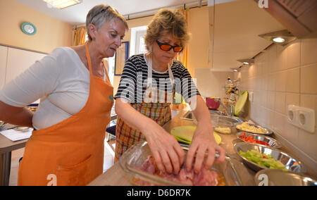 Kochen Lehrer Barbara Kunert (L) unterstützt Ilse Schmidt, der blinden und sehbehinderten ist bei der Zubereitung von Fleisch zum Braten während eines Kochkurses für Blinde und sehbehinderte Menschen in Bremen, Deutschland, 22. August 2012.  Foto: Carmen Jaspersen Stockfoto