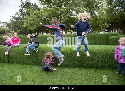 Kinder aus einer Kindertagesstätte im Stadtteil Sachsenhausen springt von einem Sofa gemacht Gras in Frankfurt Main, Deutschland, 12. September 2012. Eine Woche vor dem 2. Tag der Nachhaltigkeit in Hessen, der Umweltminister von Hessen Puttrich besucht der Riesens, grüne "MainSofa" aus Gras-, Stroh und Sisal. Es werden Veranstaltungen und Kampagnen quer durch den Staat zum Thema. Phot Stockfoto