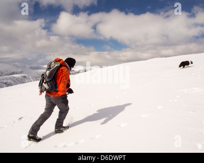 Ein Walker auf grauen Felsen mit Blick auf den Lakelandpoeten Bereich in es kaltes Wetter Ende März 2013, Lake District, Großbritannien. Stockfoto