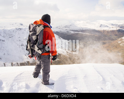 Ein Walker auf grauen Felsen wird angeschlagen durch Spindrift mit Blick auf den Lakelandpoeten Bereich im Lake District Stockfoto