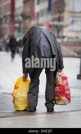 Ein älterer Mann beugt sich hinunter abholen eine schwere Plastiktüte in Frankfurt Main, Deutschland, 1. Januar 2012. Der Mann hat leere Rückerstattung Flaschen gesammelt, die die Straßen nach Silvester feiern littering sind. Foto: Frank Rumpenhorst Stockfoto