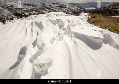 Erhöhten Fußspuren im massiven Schneeverwehungen blockieren die Kirkstone Pass-Straße über Ambleside im Lake District, Stockfoto