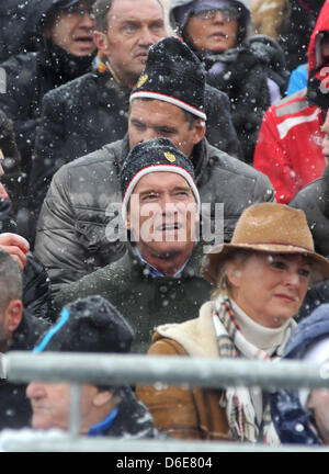 Österreichisch-US-Schauspieler und ehemalige US-Gouverneur von Kalifornien Arnold Schwarzenegger (C, vorne) und deutsche Schauspieler Ralf Moeller (C, oben) sehen die Männer bergab Hahnenkammrennen in Kitzbühel, Österreich, 21. Januar 2012. Das Elegendery-downhill-Rennen hat Alos ein Treffpunkt des Jetset. Foto: Felix Hoerhager Stockfoto