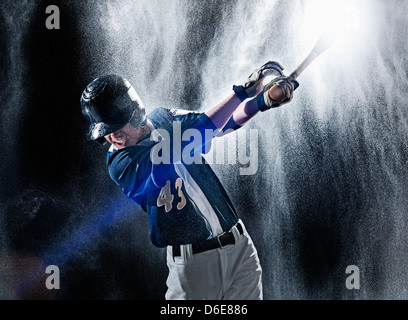 Kaukasische Baseballspieler schwingen Schläger im Regen Stockfoto