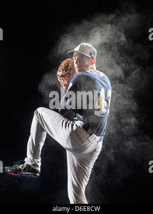 Kaukasische Baseballspieler pitching unter Kunstlicht Stockfoto