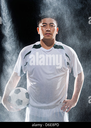 Asiatische Fußball-Spieler im Regen stehen Stockfoto