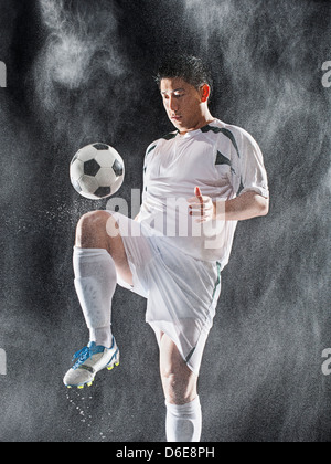 Asiatische Fußball-Spieler treten Ball im Regen Stockfoto