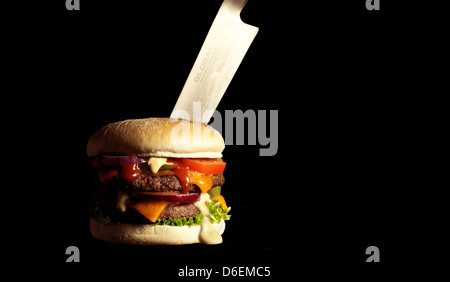 Hamburger mit großen Küchenmesser erstochen / Fett / fast Food Stockfoto