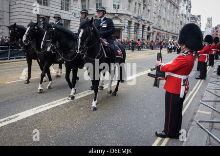 Berittene Polizisten Met Reiten vor der Beerdigung von Margaret Thatcher. Im Anschluß-Markierungsfahne drapiert und auf einer Lafette montiert, bewegt sich der Sarg des ehemaligen britischen Premierministers Baronin Margaret Thatcher Sarg entlang Fleet Street in Richtung St. Pauls Kathedrale in London, England. Gewährt einem feierlichen Begräbnis mit militärischen Ehren, nicht gesehen, seit dem Tod von Winston Churchill im Jahre 1965, erwarten Familie und 2.000 VIP-Gäste (inkl. Queen Elizabeth) ihr Gefolge. Stockfoto