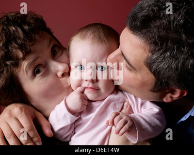 Eltern des Babys Wangen küssen Stockfoto