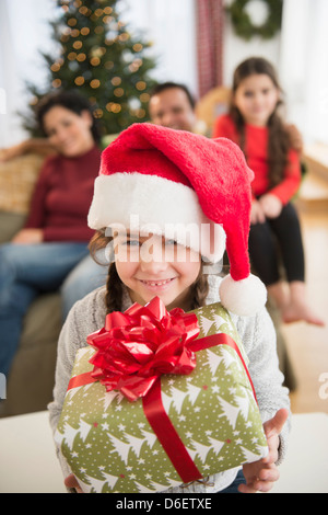 Mädchen in Weihnachtsmütze hält Weihnachtsgeschenk Stockfoto