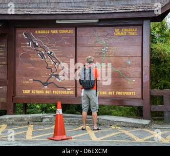 Ein Mann steht die Infotafel zum Mount Kinabalu Trail Park Hauptquartier in Sabah Borneo lesen Stockfoto