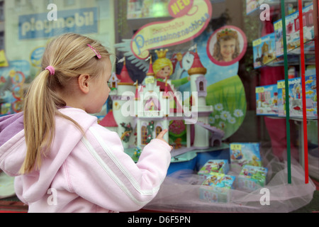 Flensburg, Deutschland, Mädchen steht vor einem geschmückten Fenster und blickt auf das Spielzeug Stockfoto